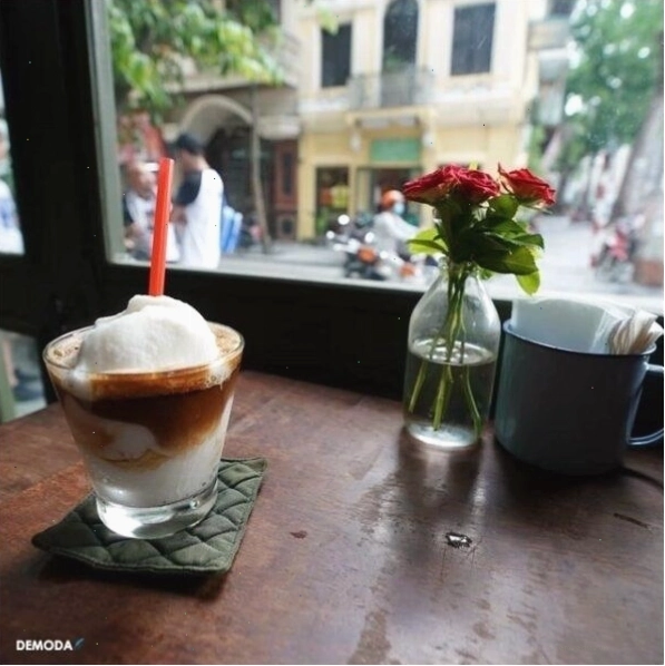 Hai người bạn ngồi đối diện nhau, cùng nhau thưởng thức cafe và trò chuyện