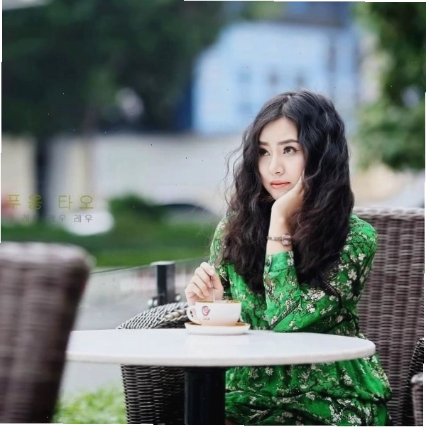 Hình ảnh bàn tay cầm ly cà phê, ngón tay gõ nhẹ lên mặt bàn
