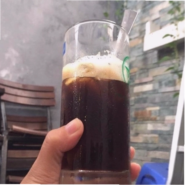 Hình ảnh cô gái mỉm cười nhẹ nhàng khi uống cà phê