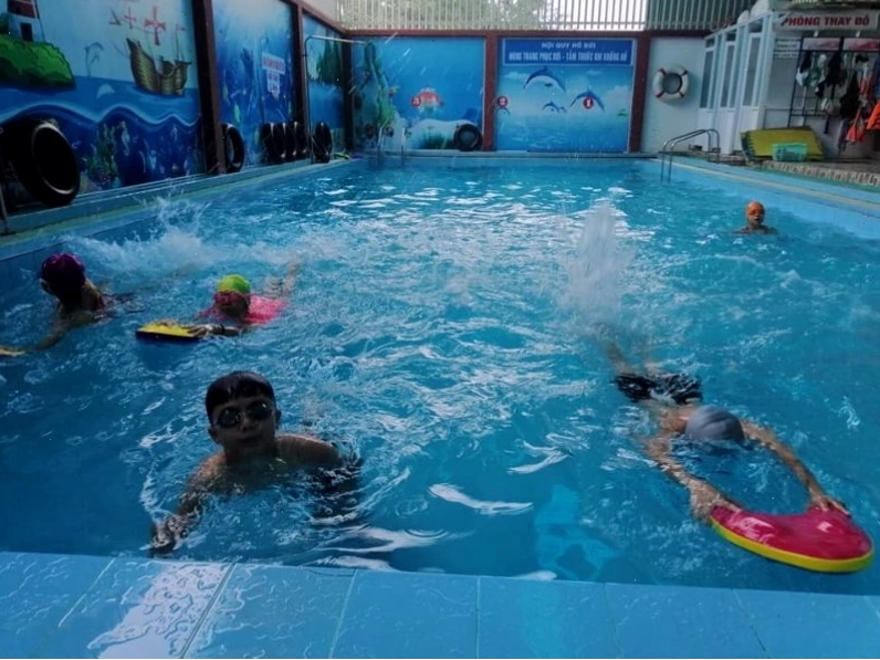 Huấn luyện viên đang hướng dẫn kỹ thuật bơi cho học viên tại Bể bơi Tuổi Trẻ