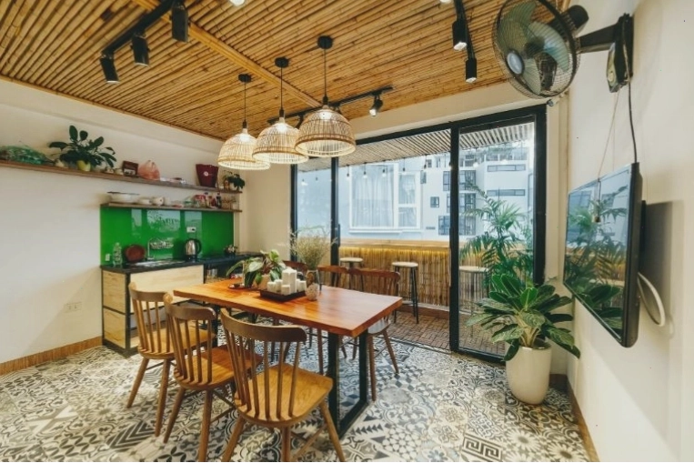 Khu vực bếp tại Aimee House sạch sẽ, đầy đủ tiện nghi và có tivi, bàn ghế