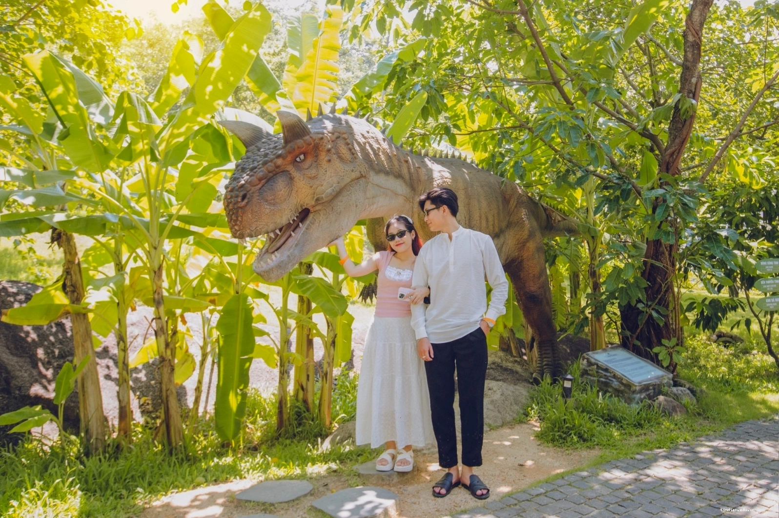 Lối đi trong công viên khủng long với cây xanh và mô hình khủng long