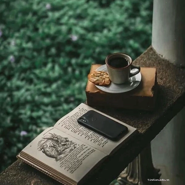 Người phụ nữ ngồi một mình tại bàn, mỉm cười nhẹ nhàng nhìn ly cà phê